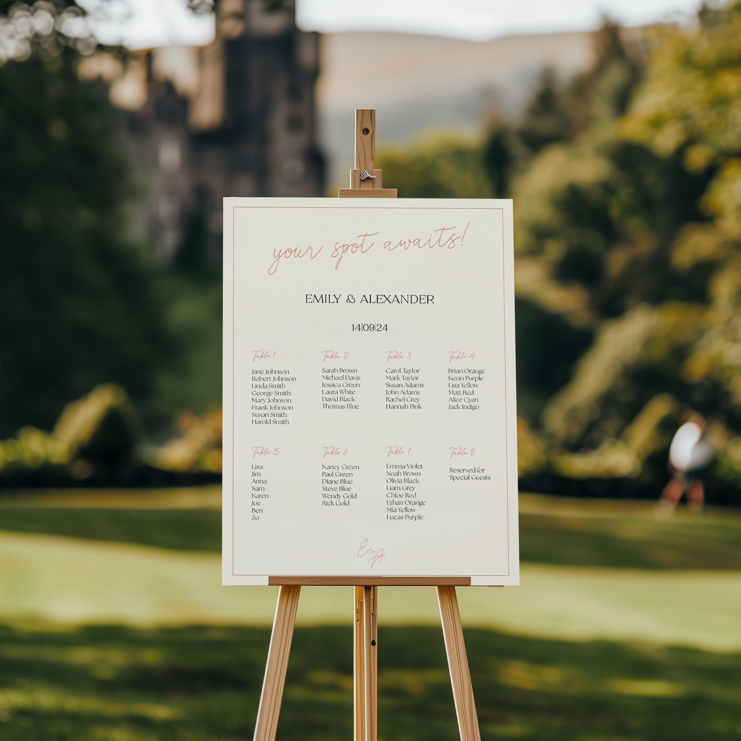 A wedding seating chart displayed on an easel in an outdoor garden setting, with a blurred castle in the background. The chart reads "Your spot awaits!" in elegant script, followed by "Emily & Alexander" and the date "14.09.24" in a modern serif font. Eight tables are listed with guest names organized beneath each, offering a clean and minimal design.