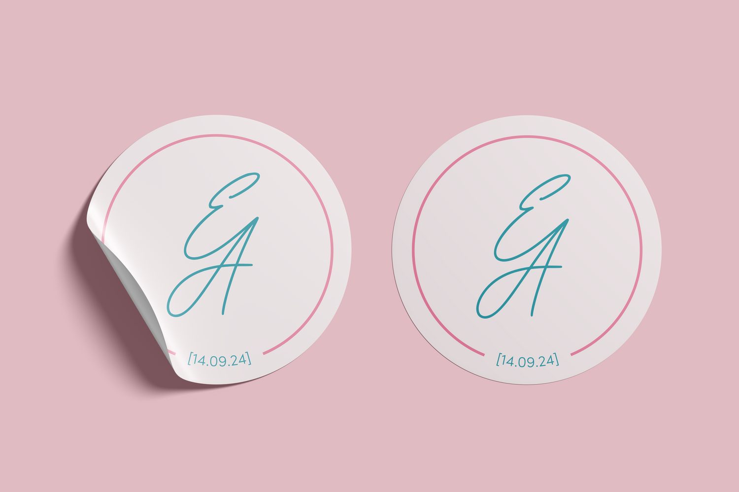 Two versions of a circular wedding sticker featuring the initials "E & A" in teal script, a pink border, and the date "14.09.24" beneath, set against a blush pink background.