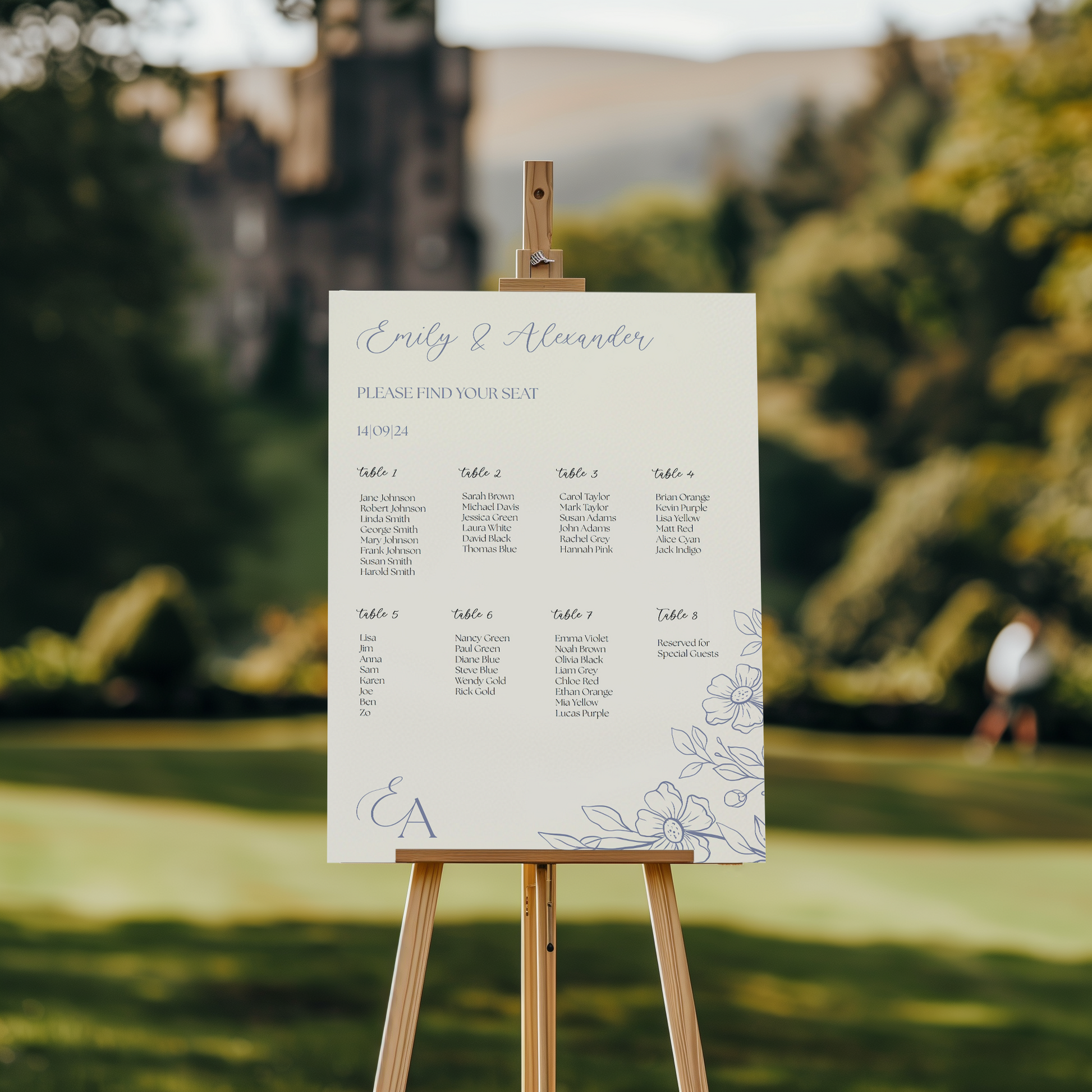 A wedding seating chart placed on an easel in an outdoor garden with a blurred castle in the background. The chart is titled "Emily & Alexander" in elegant script, followed by "Please Find Your Seat" and the date "14.09.24." Below, guest names are listed under eight different tables, each in a clean serif font. A delicate floral design adorns the bottom right corner, along with the couple's initials "E + A," adding a soft, romantic touch to the overall design.