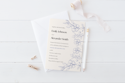 A wedding invitation laid on a white wooden surface alongside a white envelope, pencil, and decorative ribbon. The invitation includes delicate blue floral illustrations on the right edge, with text inviting guests to the wedding of Emily Johnson and Alexander Smith on 14th September 2024 at The Rose Garden Venue, followed by reception details.